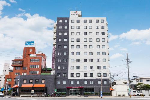 un edificio blanco alto en una calle de la ciudad en Hotel Wing International Kumamoto Yatsushiro, en Yatsushiro
