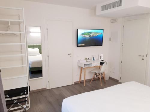 una camera con letto, scrivania e TV di Hotel Aurora Duino a Duino