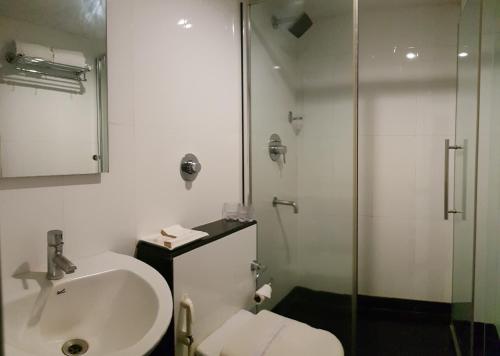 a white bathroom with a sink and a shower at Hotel Winsar Park in Visakhapatnam