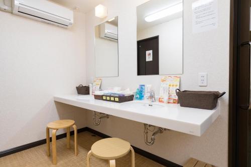 a bathroom with a white sink and two stools at Hotel Wing International Kumamoto Yatsushiro in Yatsushiro