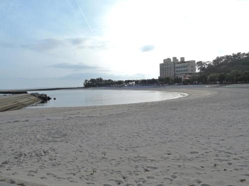 a sandy beach with a building in the background at Minshuku Osaki in Nishio