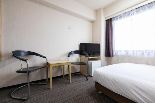 a hotel room with a bed and two chairs and a desk at Hotel Wing International Kumamoto Yatsushiro in Yatsushiro