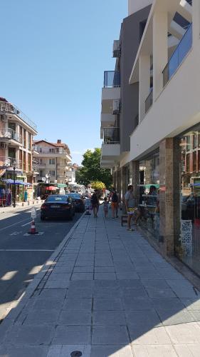 a street with people sitting on a bench in front of a building at Guesthouse Odesos in Sozopol