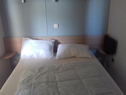 - un lit avec 2 oreillers blancs dans une chambre dans l'établissement location mobil home ****, aux Mathes