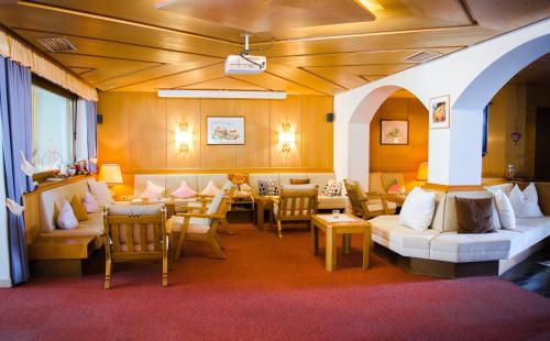a living room with couches and tables and chairs at Hotel St. Pankraz in San Pancrazio dʼUltimo