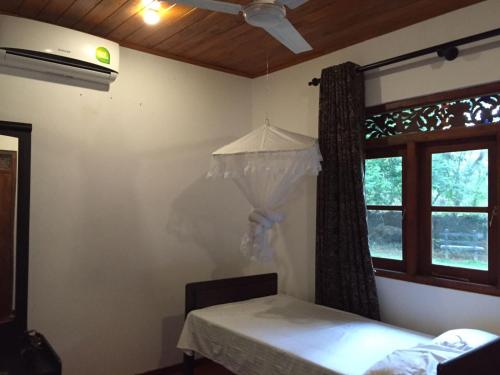 a bedroom with a bed and a window and a ceiling fan at Green Herbal Ayurvedic Eco-Lodge in Galle