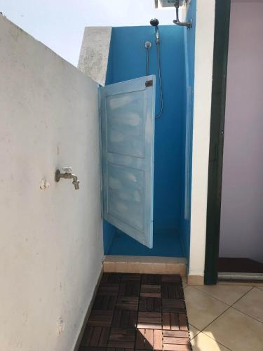 a bathroom with a shower with a blue door at Casa Torre di Ligny in Favignana