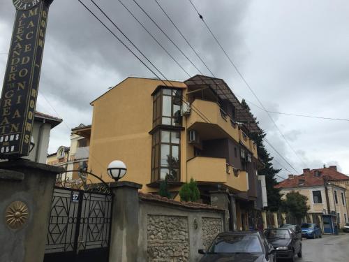 un edificio amarillo con coches estacionados frente a él en Villa Konzuli, en Bitola