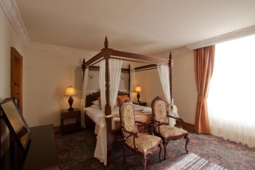 a bedroom with a canopy bed and two chairs at Duke Of Gordon Hotel in Kingussie