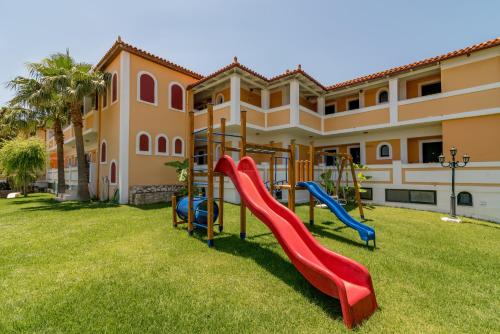 un parque infantil en un patio frente a una casa en Matilda Hotel, en Vasilikos