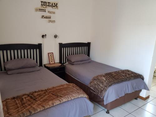 two beds sitting next to each other in a room at Kgosi Lodge in Kimberley