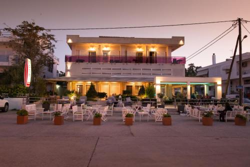 un edificio con mesas y sillas delante de él en Hotel Pithari en Agia Triada
