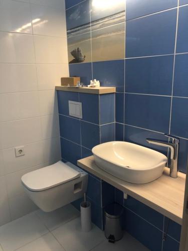 a blue tiled bathroom with a toilet and a sink at Villa RK DeLuxe in Zatoka