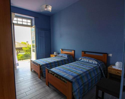 2 camas en una habitación azul con ventana en le palme, en Cannero Riviera