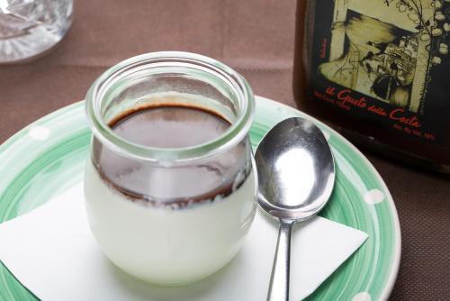 a glass of milk on a plate with a spoon at Hotel Orso Bruno in Carate Urio