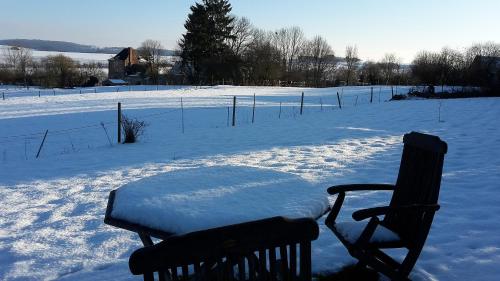 a bench covered in snow next to a snow covered field at Les Hauts de Crupet in Maillen