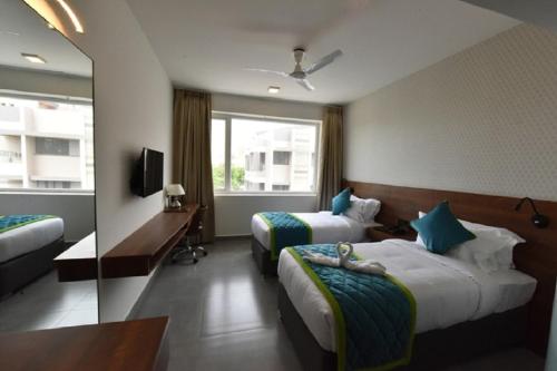 a hotel room with two beds and a television at Vivid A Boutique Hotel in Tiruchchirāppalli