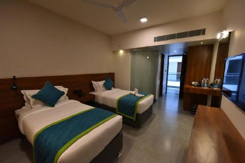 a hotel room with two beds and a flat screen tv at Vivid A Boutique Hotel in Tiruchchirāppalli