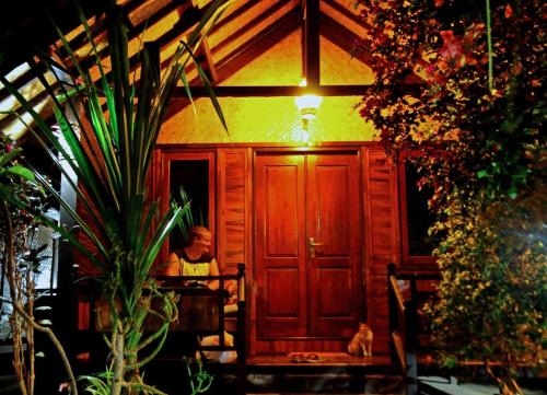 a man sitting in the doorway of a house with a cat at Gili Flush Harmony in Gili Trawangan