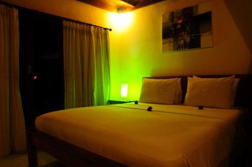a bedroom with a white bed with a green light at Gili Flush Harmony in Gili Trawangan