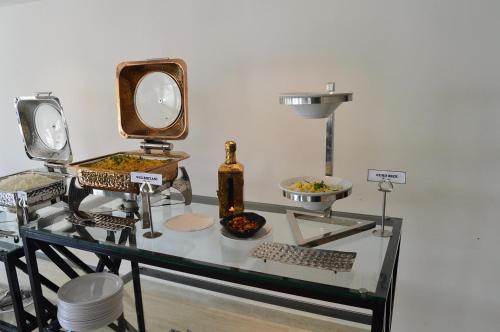 a glass table with food and a bottle on it at Vivid A Boutique Hotel in Tiruchchirāppalli