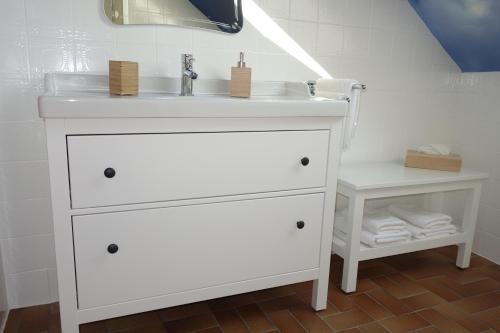 a white bathroom vanity with a sink and a shelf at Ostseezauber in Pelzerhaken