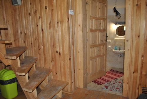 a bathroom with wooden walls and a sink and stairs at Chata Reľov in Reľov