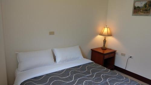 a bed in a bedroom with a lamp on a night stand at 168 Living Water in Dongshi