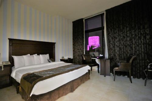 a bedroom with a bed and a desk and a window at Hisham Hotel in Amman
