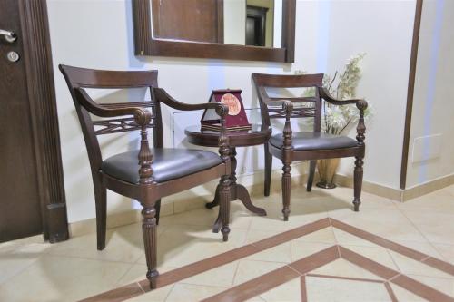 two wooden chairs and a table with a mirror at Hisham Hotel in Amman