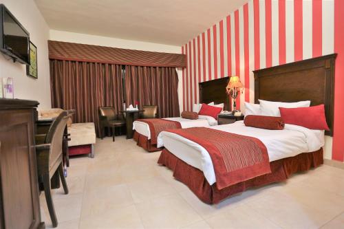 a hotel room with two beds and a desk at Hisham Hotel in Amman