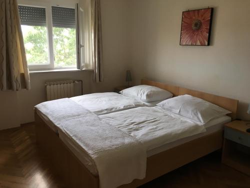 a bedroom with a bed with white sheets and a window at Apartmaji Zonta in Koper