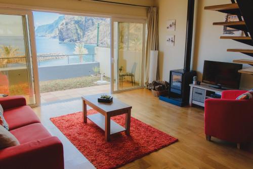 a living room with a red couch and a table and a television at Sunrise House in Ponta Delgada