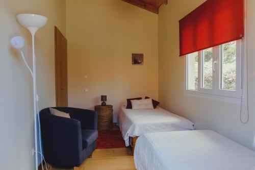 una camera da letto con due letti, una sedia e una finestra di Sunrise House a Ponta Delgada