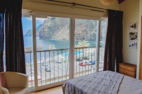 a bedroom with a large window with a view of the ocean at Sunrise House in Ponta Delgada