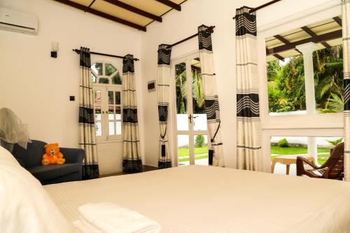 a bedroom with a bed and a couch and windows at Ann Villa Negombo in Negombo