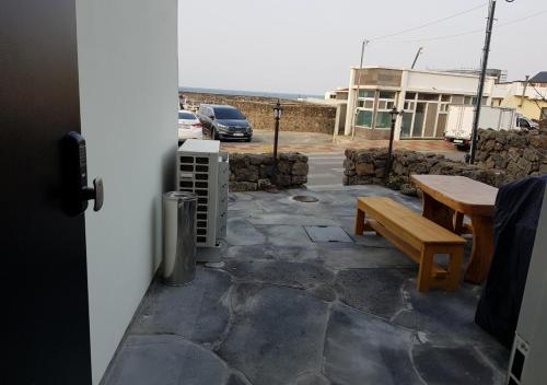 a patio with a wooden bench and a table at HANI Haus in Jeju