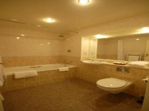 a bathroom with a tub and a toilet and a sink at Wolds Village Hotel in Bainton