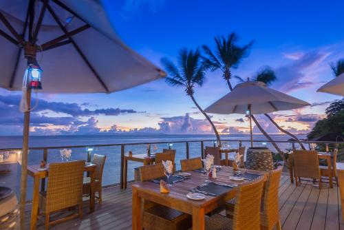 a table on a deck with a view of the ocean at Coco de Mer Hotel and Black Parrot Suites in Grand'Anse Praslin