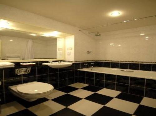 a bathroom with a toilet and a sink and a tub at Wolds Village Hotel in Bainton