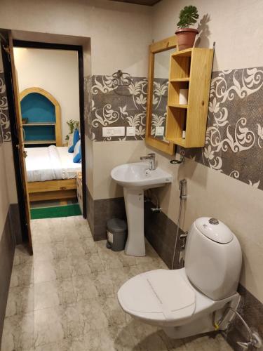 a bathroom with a toilet and a sink and a bed at Jharipani Castle in Mussoorie