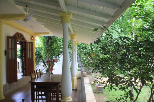 a porch with columns and a table and chairs at Dionis Villa in Unawatuna