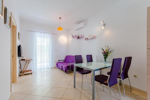a dining room with a table and purple chairs at Holiday house Barbara in Supetar