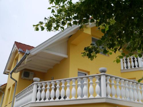 a yellow house with a white railing on a balcony at Hévíz -Alsópáhok Villa-Erika Apartman in Alsópáhok