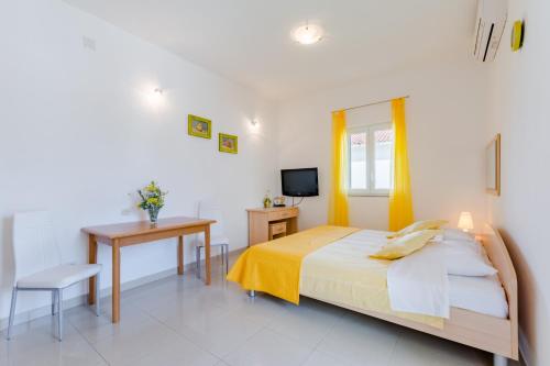 a bedroom with a bed and a desk and a television at Holiday house Barbara in Supetar