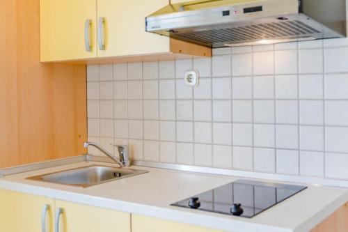 a kitchen with a sink and a white tiled wall at Holiday house Barbara in Supetar