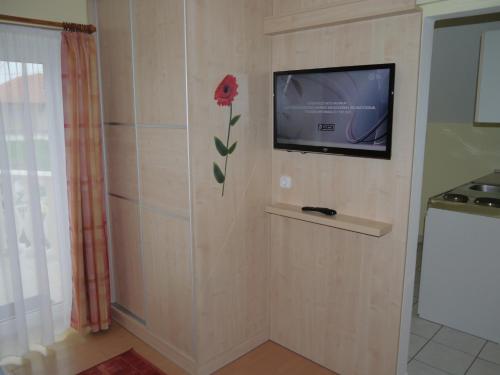 a room with a television and a flower on the wall at Hévíz -Alsópáhok Villa-Erika Apartman in Alsópáhok
