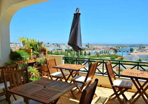 un patio con mesas de madera y sillas en el balcón en Tavira Terrace en Tavira