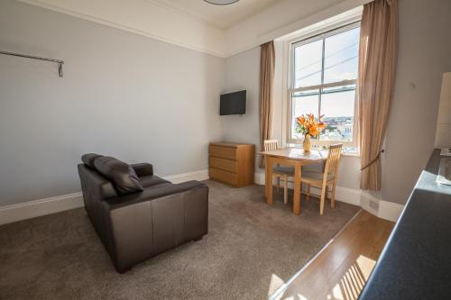 a living room with a couch and a table and a window at Clydesdale Apartments in Torquay