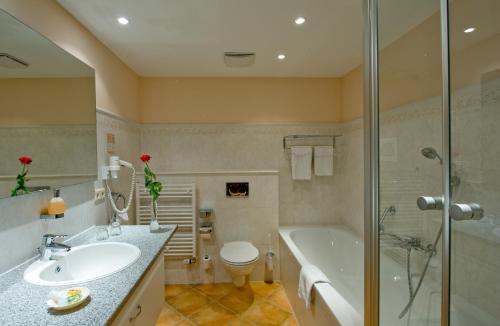 a bathroom with a sink and a tub and a toilet at Hotel Habichtstein in Alexisbad